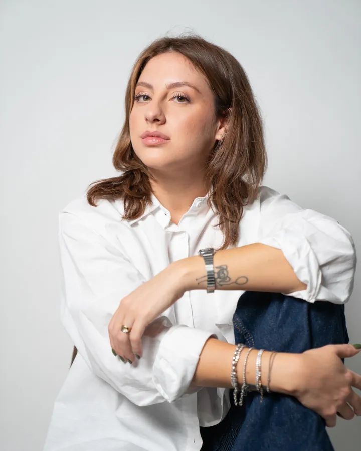 Francesca seduta in camicia bianca, le braccia sul ginocchio