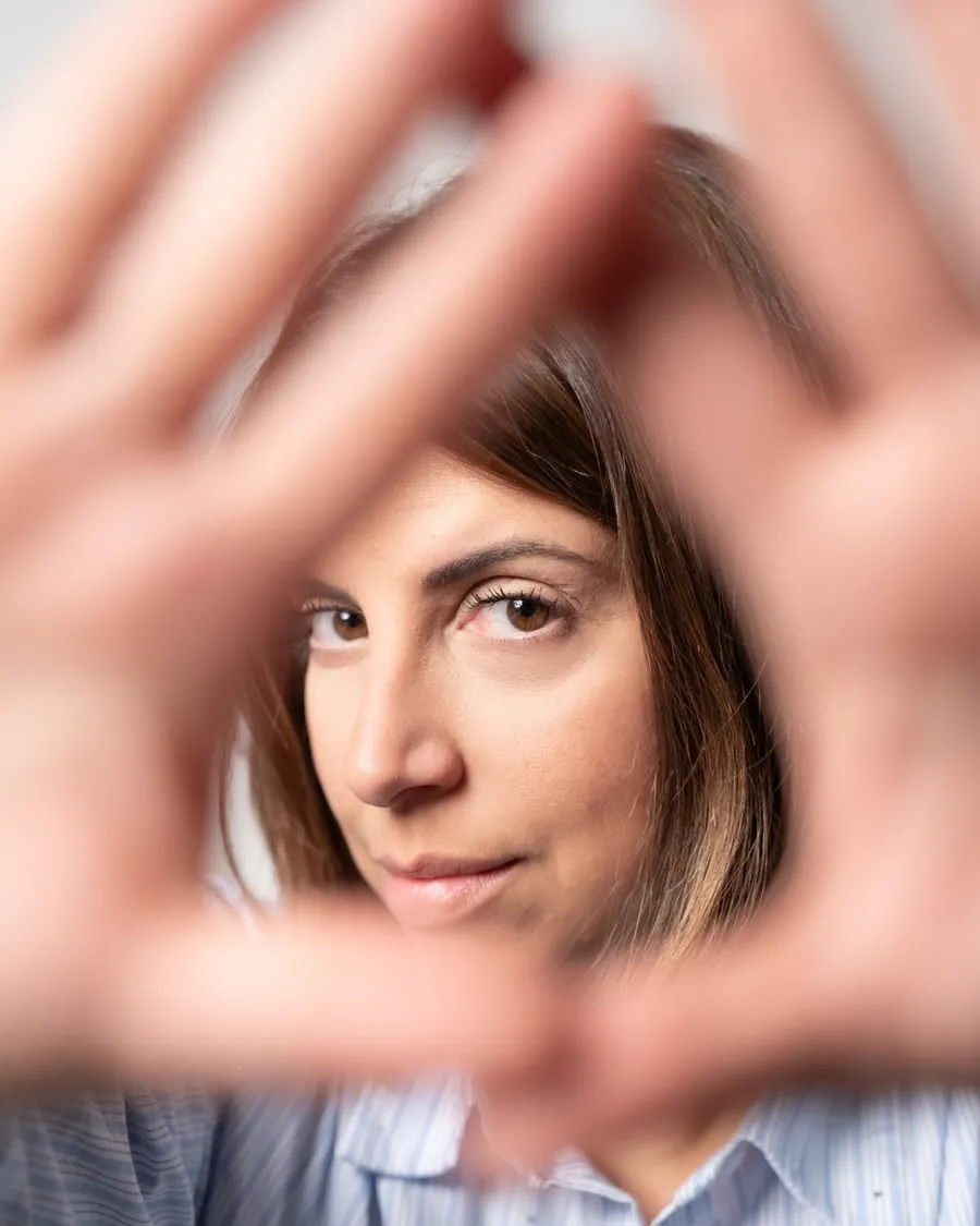 Antonella guarda in camera attraverso le mani a forma di triangolo